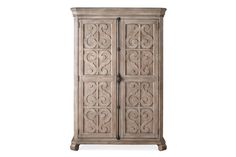 an ornate wooden armoire with carvings on the front and side panels, in grey wood