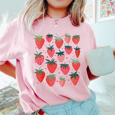 Our strawberry fruit shirt makes the perfect addition to your summer wardrobe.  You will love it! This shirt is made with a professional DTG Printing machine. Printed with eco-friendly water based inks that prints the image/designs on the shirt allowing the image to become part of the shirt so there is no peeling or cracking over time. If you have any questions please feel free to reach out and I will be happy to assist you.  HOW TO ORDER  1. Select the size and color of the shirt you would like Relaxed Fit Heart Print T-shirt For Summer, Trendy Heart Graphic T-shirt For Summer, Trendy Pink T-shirt With Heart Print, Pink Short Sleeve Shirt With Strawberry Print, Pink Fruit Print Tops For Summer, Sweet Red Summer Tops, Cute Strawberry Print Shirt For Spring, Pink Strawberry Print Shirt For Summer, Sweet Strawberry Print Crew Neck Top