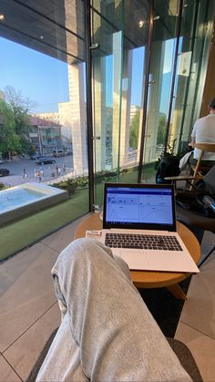 an open laptop computer sitting on top of a wooden table next to a swimming pool