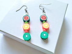 a pair of earrings with fruit on them sitting on top of a white countertop