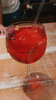 a drink sitting on top of a wooden table next to a person holding a knife