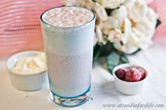 a tall glass filled with liquid next to some flowers