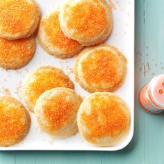 several biscuits are on a white plate next to two glasses of juice and an orange drink