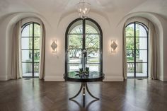 an elegant foyer with arched windows and chandelier in the center is flanked by two circular doorways