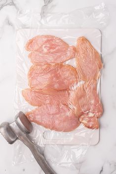 raw chicken pieces on a plastic bag with a spoon and fork next to them,