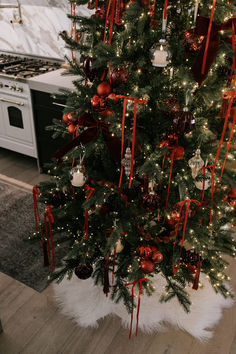 a decorated christmas tree in a kitchen with red and white ornaments on the trees branches