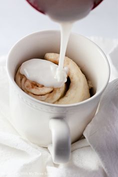 a glass of wine being poured into a white cup filled with bananas and cinnamons