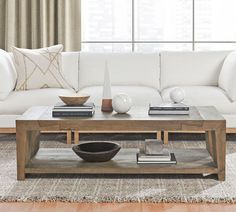 a living room with a white couch, coffee table and books on the end tables