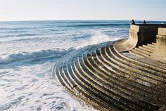 people are standing on the edge of an ocean wall