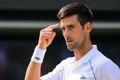 a male tennis player is holding his hand up to the side while looking at something