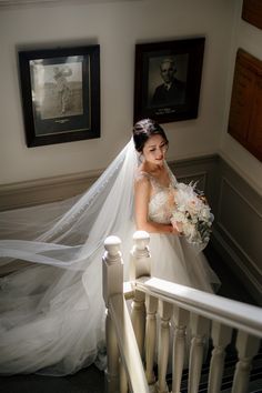 a woman in a wedding dress is standing on the stairs with her veil flying over her head