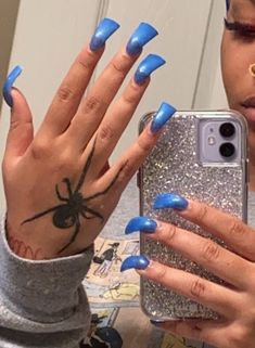 a woman with blue nail polish holding up her phone