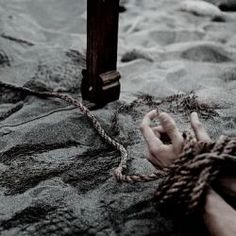 a person tied up to a cross on the ground with their hand in front of them