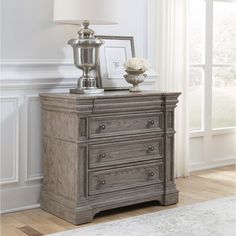 a nightstand with a lamp on top of it next to a white rug and window