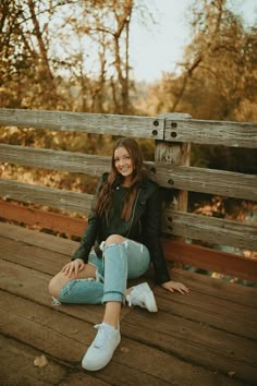 a woman sitting on the ground with her legs crossed and wearing white tennis shoes, smiling