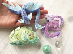 someone is holding three small dragon toys in their hand