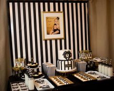 a black and white dessert table with cake, cupcakes, and other treats