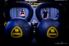 a man and woman standing behind kettles in a gym