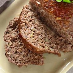 two slices of meatloaf on a white plate with green garnishes