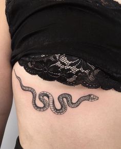 a woman's stomach with a snake tattoo on her lower side ribcage