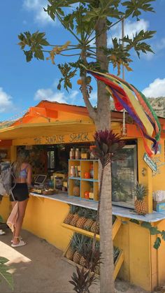 a woman standing in front of a food stand with pineapples on the counter