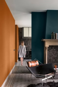 a woman is walking down the hall way in her living room with blue and orange walls