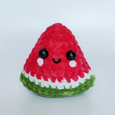 a small stuffed watermelon sitting on top of a white table next to a red and green object