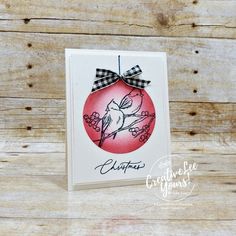 a christmas ornament with a bow hanging from it on a wooden table next to some wood planks