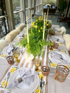 the table is set with yellow flowers and candles