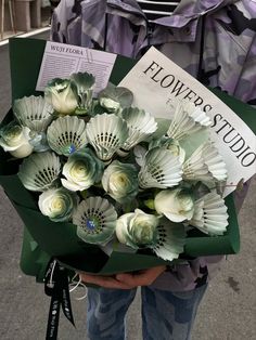 a person holding a bouquet of flowers and a sign with the words flowers studio on it