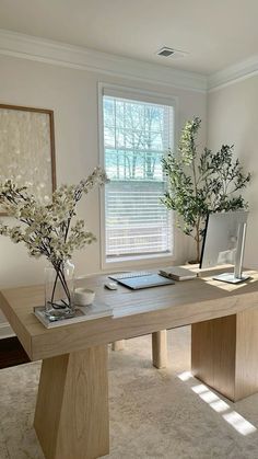 two vases with flowers are sitting on a table in front of a window,