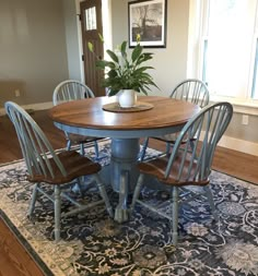 a dining room table with four chairs and a potted plant in the corner on top