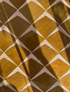 the shadow of a person's feet on a tiled floor with a phone in their hand