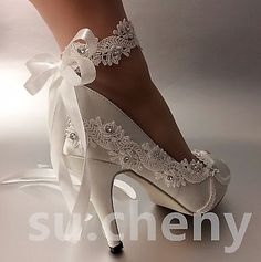 a woman's white high heeled wedding shoes with lace and pearls on the side