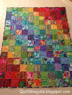 a colorful quilt is hanging on the wall in front of a tile floor with white tiles