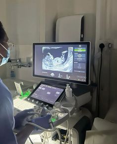 a person wearing a surgical mask looking at a computer screen with an x - ray image on it