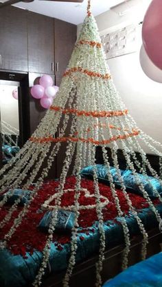 a bed decorated with beads and balloons in a room that has a christmas tree hanging from the ceiling