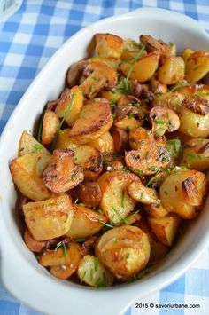 a white bowl filled with potatoes on top of a blue and white checkered table cloth