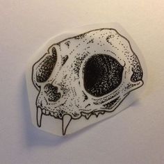 a sticker with an image of a skull on it's side and the bottom part of its head in black ink