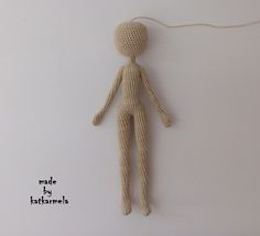 a crocheted doll hanging from a string on a white wall with the caption made by katemea