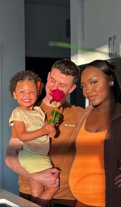 a man, woman and child are holding a rose