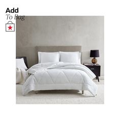 a bed with white comforter and pillows on it in a room next to a lamp