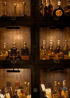 the shelves are filled with liquor bottles and other items in glass cases, all lit up at night