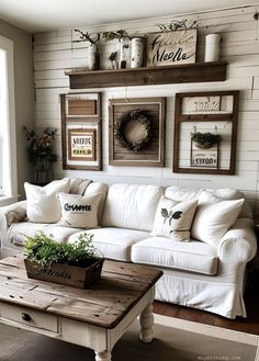 a living room with white couches and wooden shelves on the wall above them is decorated with greenery