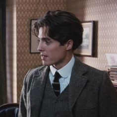 a man wearing a suit and tie standing in front of a desk