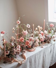 a table topped with lots of pink flowers and candles