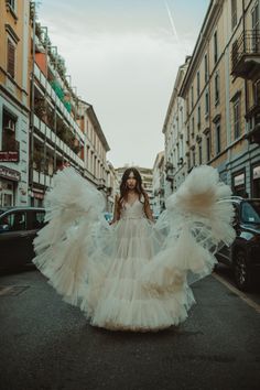 a woman is walking down the street in an angel dress