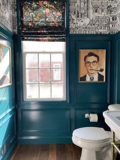 a bathroom with a toilet, sink and pictures on the wall above it's windows