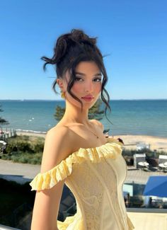 a woman in a yellow corset standing on a balcony next to the ocean