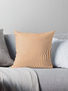 an orange and white pillow sitting on top of a gray couch